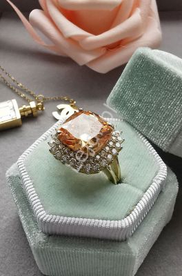 Elegancki pierscionek w kolorze różówego złota z dużym pomarańczowym kryształkiem otoczonym przez cy
